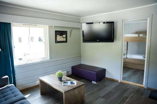 a living room with a couch and a tv on the wall at Hemsedal Cafe Skiers Lodge in Hemsedal