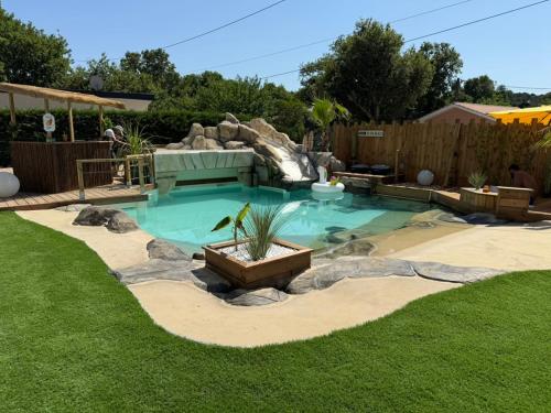 a swimming pool with a waterfall in a yard at Maison du Lac avec Lagon, Spa de Nage, Jacuzzi in Biscarrosse