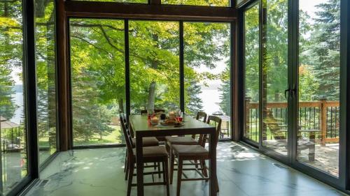 a dining room with a table and chairs and large windows at Lake Muskoka 3-bdrm Cottage - Pier 100 #70 in Port Carling