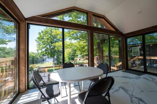 卡灵港Lake Muskoka Deluxe 2-bdrm Cottage - Pier 100 #60的一间有桌子、椅子和窗户的房间