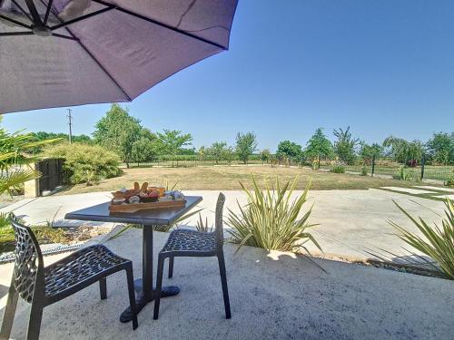 a table with two chairs and an umbrella at L inarretable studio independant in Cubnezais