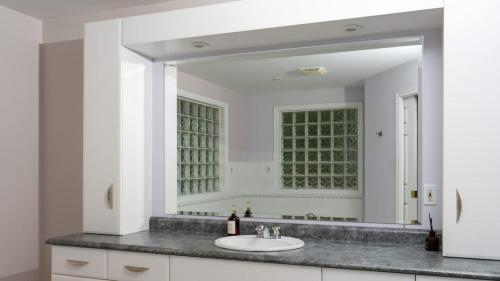 a bathroom with a sink and a large mirror at Muskoka Lakefront 4-bdrm Guest House in Port Carling