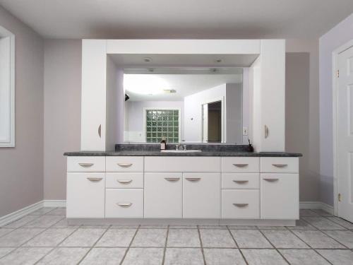 a white bathroom with a sink and a mirror at Muskoka Lakefront 4-bdrm Guest House in Port Carling