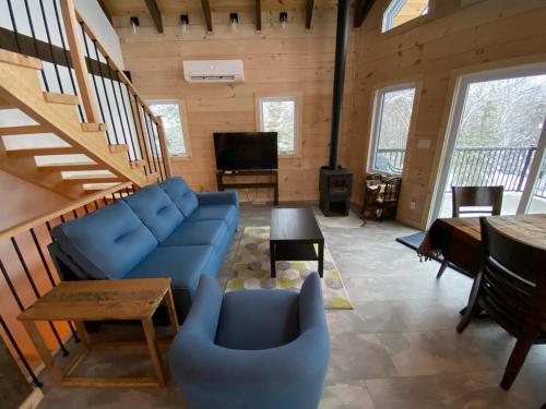 ein Wohnzimmer mit einem blauen Sofa und einem Tisch in der Unterkunft Chalet au coeur des montagnes in LʼAnse-Saint-Jean
