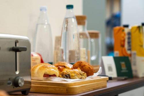 a cutting board with pastries on a counter next to a toaster at Corte Atenea Guest House Experience & Spa in Agrigento