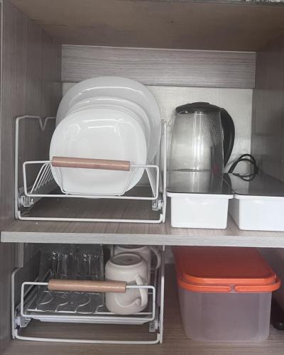 - une étagère de cuisine avec des assiettes et des ustensiles dans l'établissement Mazal Residence, à Manille