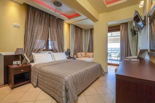 a hotel room with a bed and a television at Meliton Inn Hotel & Suites by the beach in Neos Marmaras