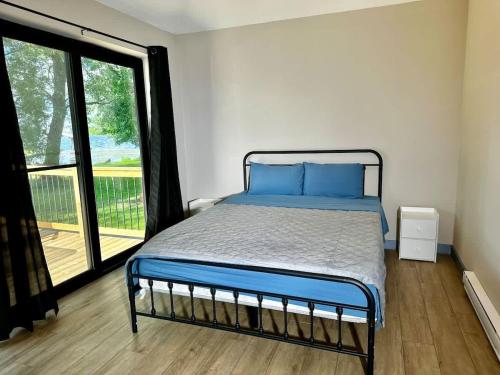 a bedroom with a bed and a large window at 2-bedroom Lake Front Cottage in Harwood ON #7 in Harwood