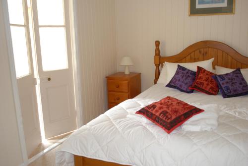 Un dormitorio con una cama blanca con almohadas y una ventana en Twisted Gum Vineyard Cottage, en Ballandean