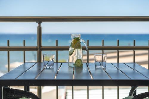 a table with a bottle and two glasses on it at Meliton Inn Hotel & Suites by the beach in Neos Marmaras