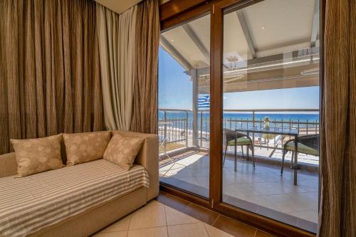 a living room with a couch and a balcony with the ocean at Meliton Inn Hotel & Suites by the beach in Neos Marmaras