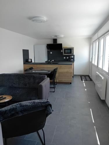 a living room with a couch and a desk at Maison proche centre-ville et baignade in L'Aiguillon-la-Presqu'île