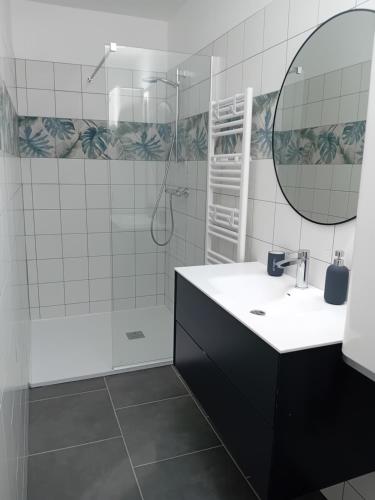 a bathroom with a sink and a shower and a mirror at Maison proche centre-ville et baignade in L'Aiguillon-la-Presqu'île
