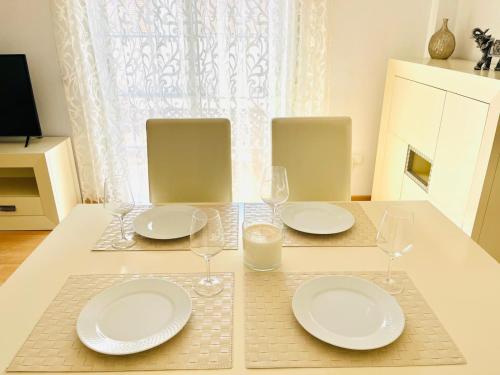 a table with two white plates and glasses on it at Sol y Relax en tu Chalet Pareado in Aguadulce