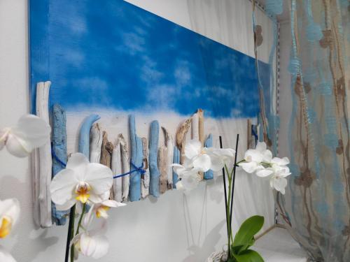 a wall with some white flowers and a blue painting at Villa Sette Nani in Torre Lapillo
