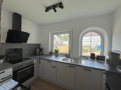 a kitchen with white cabinets and a sink and a window at Ferienhaus Dorfblick in Günzburg
