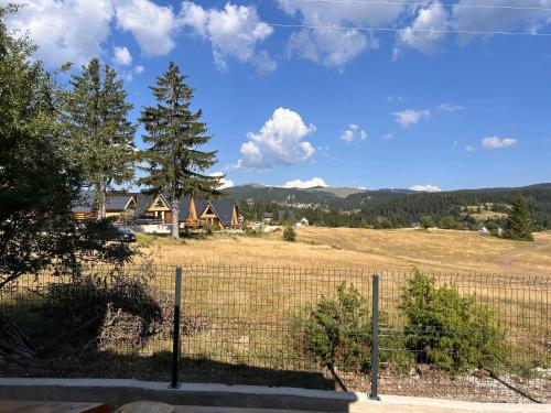 a fence in front of a field with houses at Vikendica Nuhanović - Vlašić in Vlasic