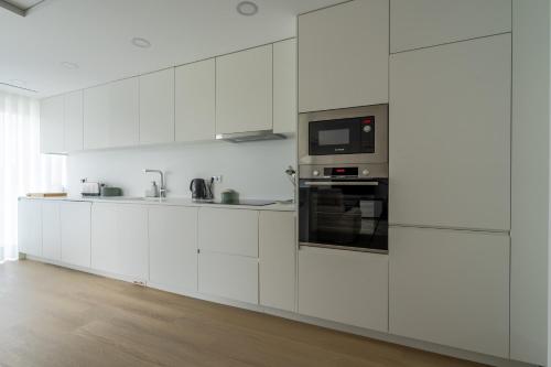 a white kitchen with white cabinets and a microwave at Premium Stay Barcelos in Vila Boa