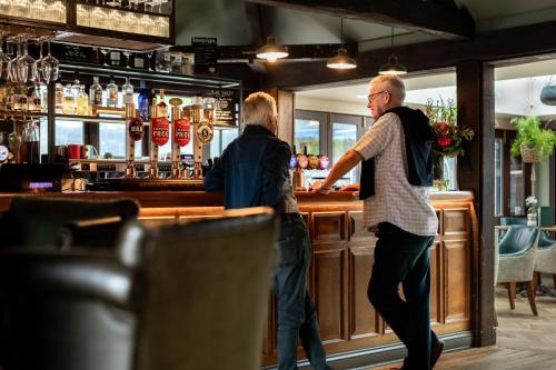 two men standing at a bar at Cromwell Arms Country Pub with Rooms in Romsey