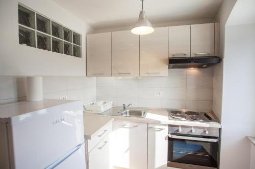 a white kitchen with a sink and a stove at Apartment Pogled na luku in Cres