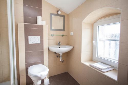 a bathroom with a toilet and a sink and a window at Apartment Pogled na luku in Cres