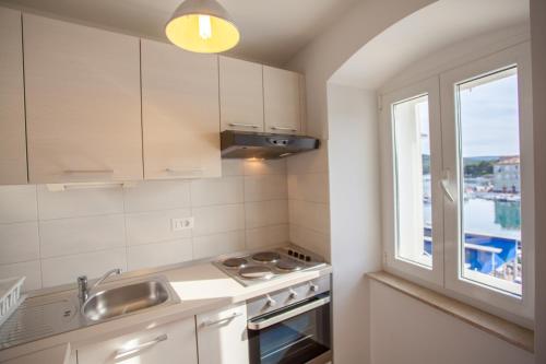 a kitchen with a sink stove and a window at Apartment Pogled na luku in Cres