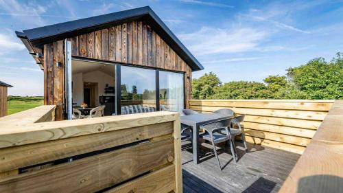 a wooden house with a deck with a table and chairs at The Rewind Retreat in Sandwich