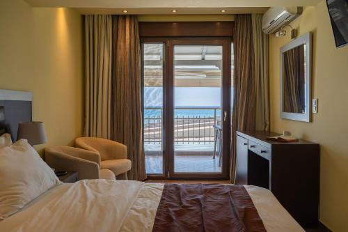 a hotel room with a bed and a balcony at Meliton Inn Hotel & Suites by the beach in Neos Marmaras