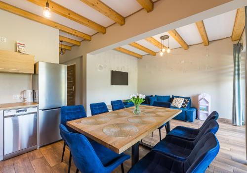 a kitchen and dining room with a wooden table and blue chairs at Solina Bóbrka Apartamenty PanDamazy 530-487-636z widokiem na kamieniołom i Zalew Myczkowiecki in Solina