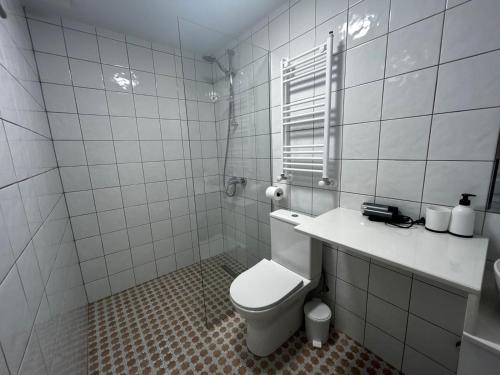 a white tiled bathroom with a toilet and a window at Pitna Guest House in K'obulet'i