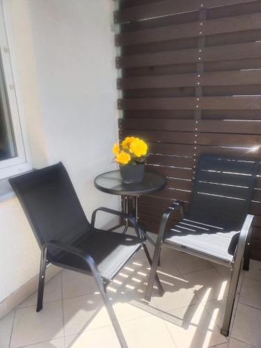 two chairs and a table with a vase of yellow flowers at Apartament Kossaka in Elblag