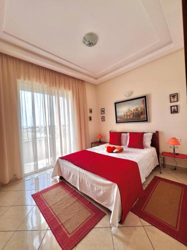 a bedroom with a large bed with red pillows at Villa près de la mer, sidi rahal route de dar bouazza in Bir Jedíd Saint-Hubert