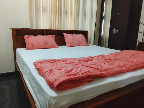 Una cama con sábanas rojas y almohadas. en Stylish 2BHK Near Adyar Gardens Mangalore, en Kankanādi