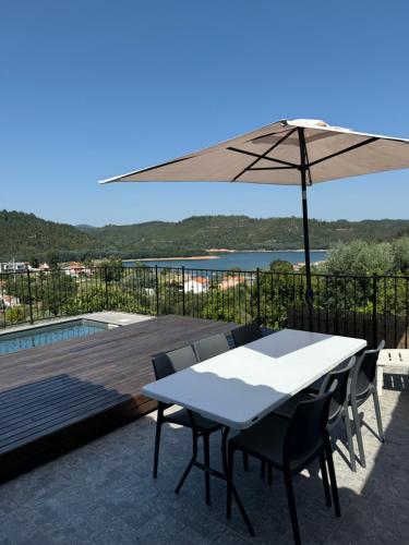a table and chairs with an umbrella on a deck at Casa Rio, Amalia in Ferreira do Zêzere
