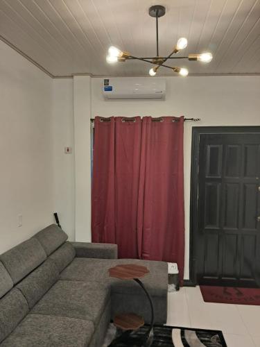 a living room with a couch and a red curtain at Cozy Home Away in Beterverwagting