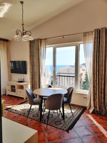a dining room with a table and chairs and a large window at Mila & Aleksandr Apartments in Budva