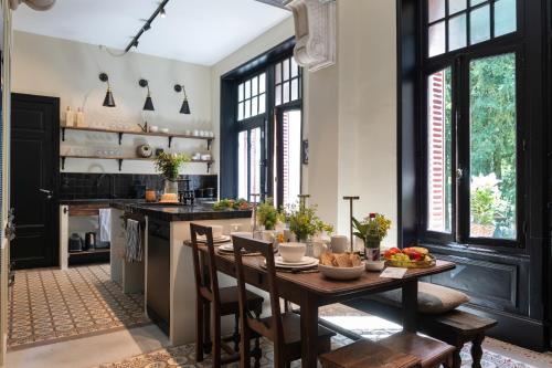 une cuisine avec une table et des chaises en bois ainsi qu'une cuisine avec des fenêtres dans l'établissement Les Villas du Parc - Chambres d'hôtes AMBROISE & GERMAINE - Meublé 5 étoiles VILLA MARIE 2 à 5 chambres, à Vittel