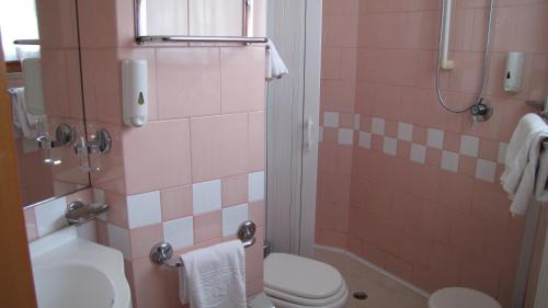 a bathroom with a toilet and a shower with pink tiles at Hotel Lanterna in Porto San Giorgio