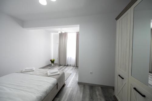 a white bedroom with a bed and a dresser at Casa Timiș in Vişeu de Sus