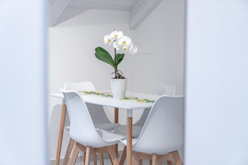 a white dining room table with white chairs and a vase of flowers at Dimora Zagara in Amalfi