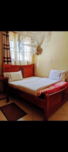 a bed sitting in a room with a window at Placewood Hotel in Masaka