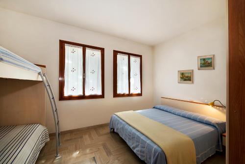a bedroom with two beds and two windows at Villa Albina in Eraclea Mare