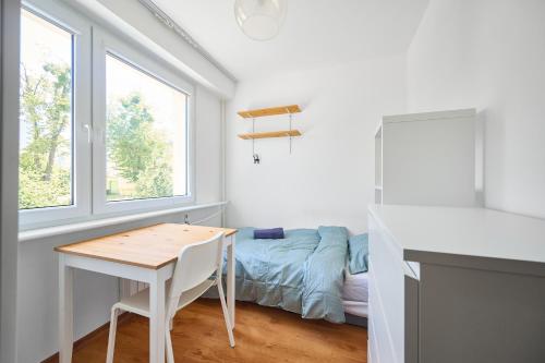 a white room with a table and a bed at Korczak Centrum Olsztyn in Olsztyn