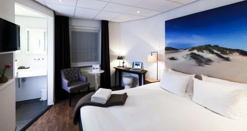 Habitación de hotel con cama grande y escritorio. en Boutique Hotel De Smulpot en Den Burg