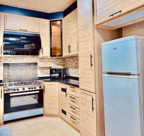 a kitchen with wooden cabinets and a white refrigerator at Modern Apartment in Prime Location - Jabal Amman in Amman