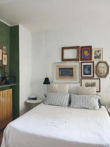 a bedroom with a large white bed with pictures on the wall at RaMaya casa d'artista 2 in Biella