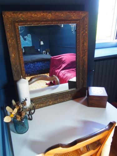 a mirror on a table in a room with a bed at La Sorcière et le Korrigan in Paimpont