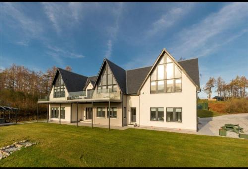 a large white house with a black roof at MacGregor Ranch Apartment in Spean Bridge