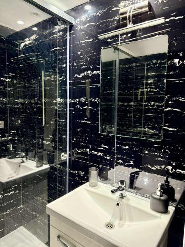 a black tiled bathroom with a sink and a mirror at Pashaj Himare Guest House in Himare