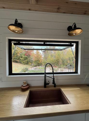 a sink in a kitchen with a window above it at H&N Tiny Home in Juno